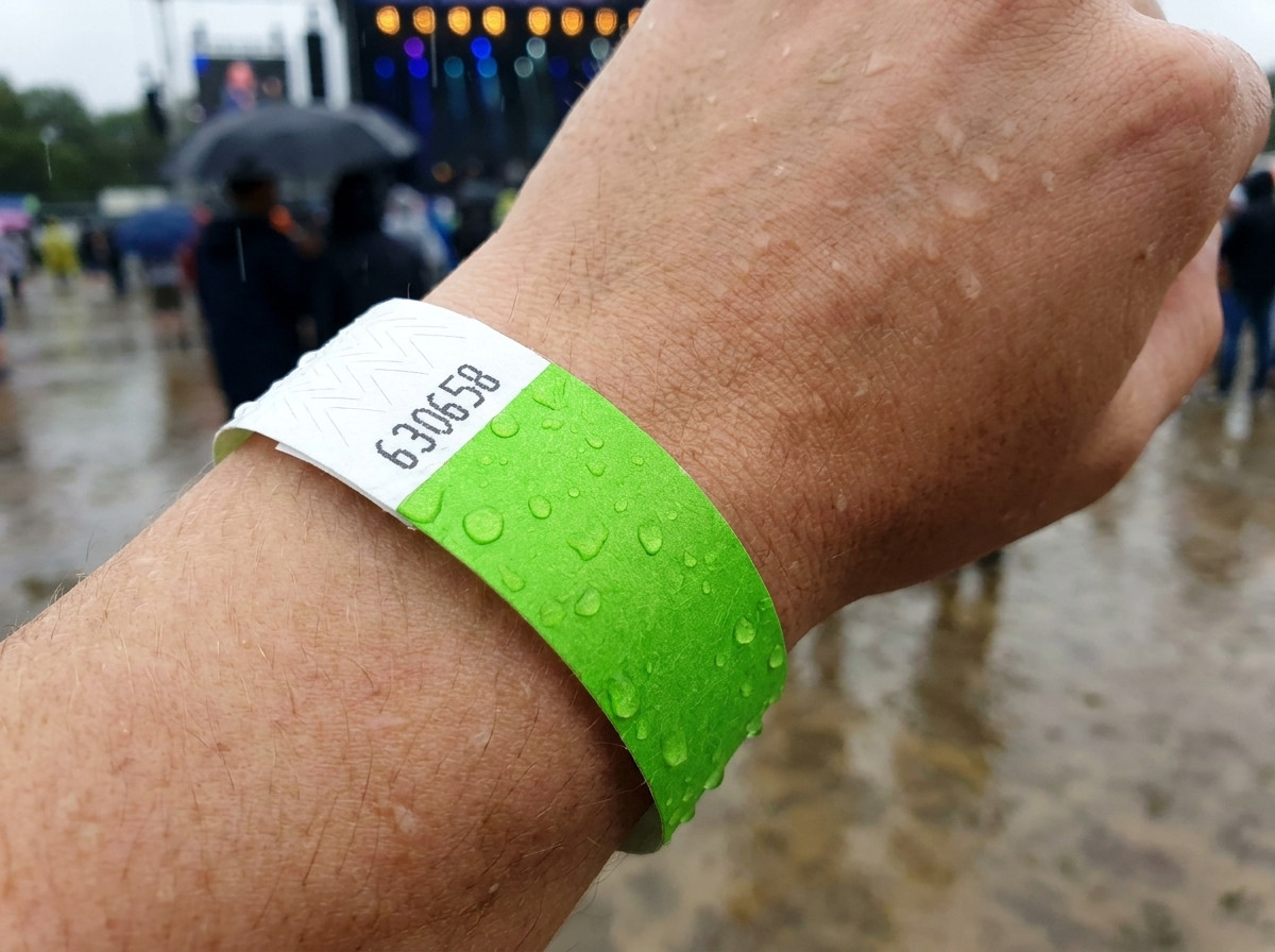 Identifikationsarmband am Handgelenk im Regen bei einem Open-Air-Festival, das seine Wasser- und Feuchtigkeitsbeständigkeit veranschaulicht